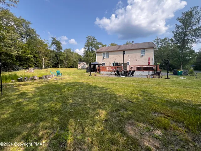 a view of a swimming pool with lawn chairs and a big yard