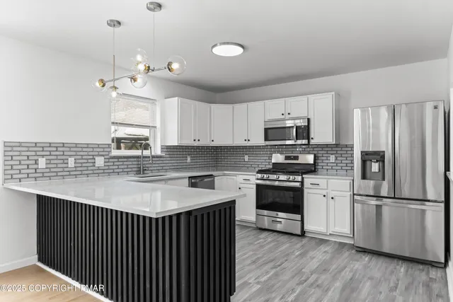 a view of an empty room with wooden floor and a table