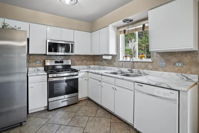 a kitchen with stainless steel appliances granite countertop a sink a stove a microwave and a refrigerator