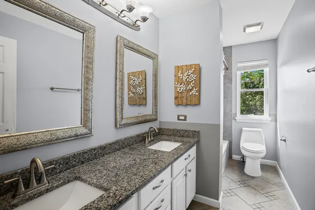 a bathroom with a granite countertop sink mirror vanity and toilet