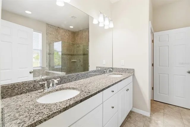 a bathroom with a granite countertop double vanity sink and a mirror
