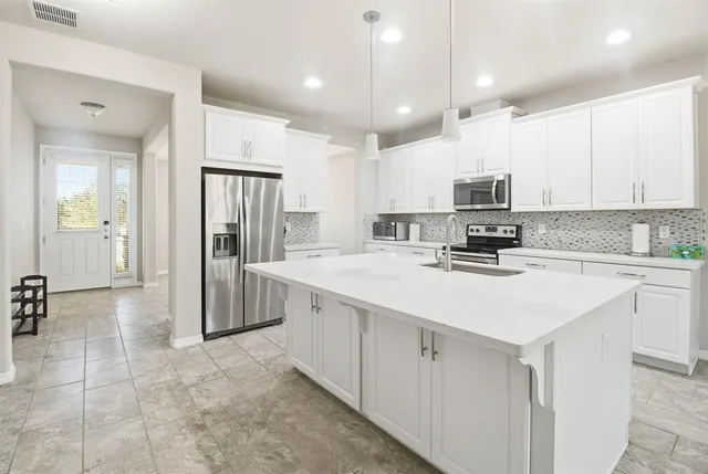 a kitchen with kitchen island granite countertop a sink appliances cabinets and furniture