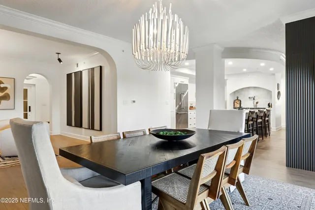 a kitchen with stainless steel appliances kitchen island granite countertop a refrigerator a stove a sink a dining table and chairs with wooden floor