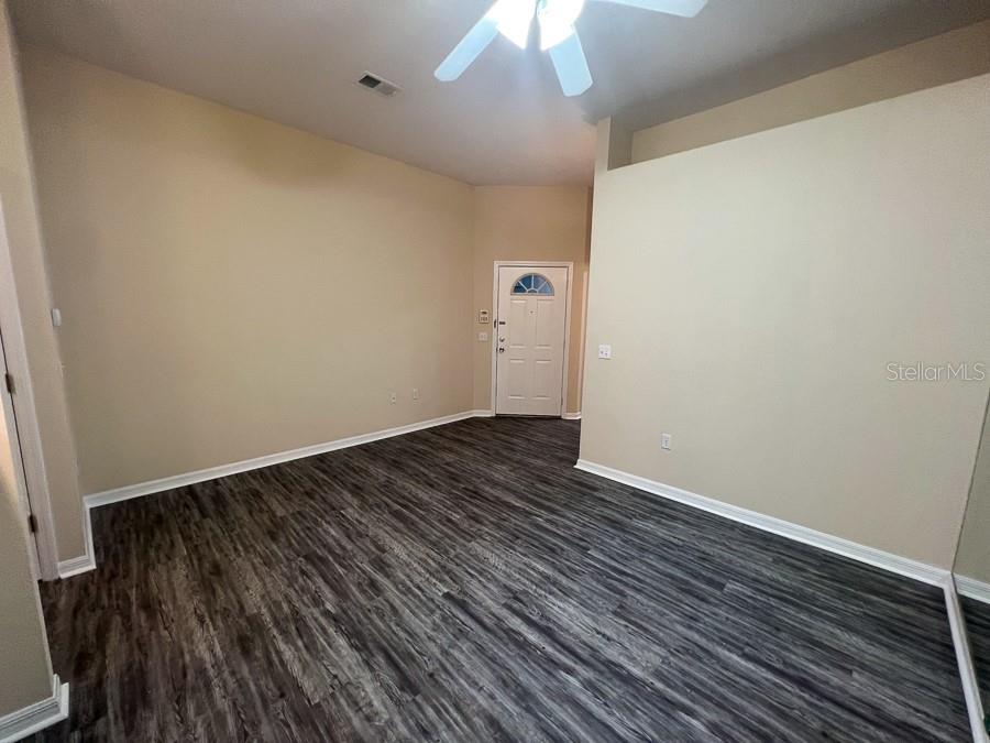 4014 Southwest 26th Drive, Unit 27 Gainesville, FL 32608 - Photo 7 of 15 a view of an empty room with wooden floor and a ceiling fan