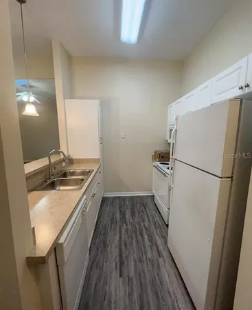 a kitchen with a refrigerator a sink and wooden floor