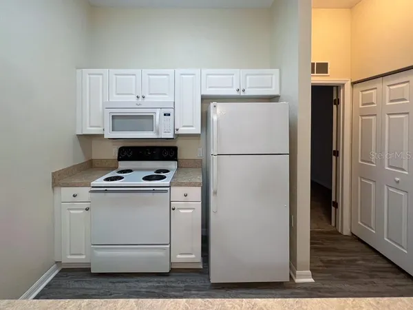a white refrigerator freezer and a stove sitting inside of a kitchen