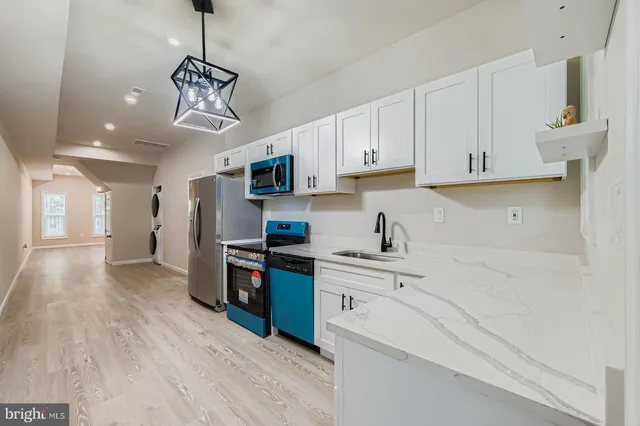 a kitchen with kitchen island granite countertop a sink cabinets and stainless steel appliances
