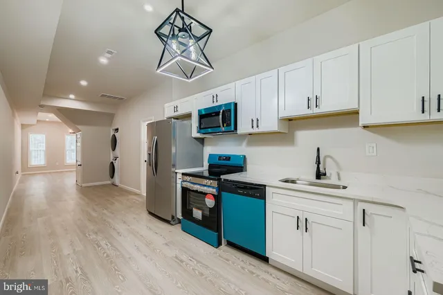 a kitchen with stainless steel appliances granite countertop a refrigerator a sink dishwasher a stove and white cabinets with wooden floor