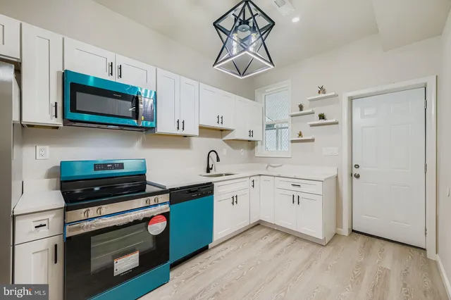 a kitchen with stainless steel appliances a stove a sink and white cabinets