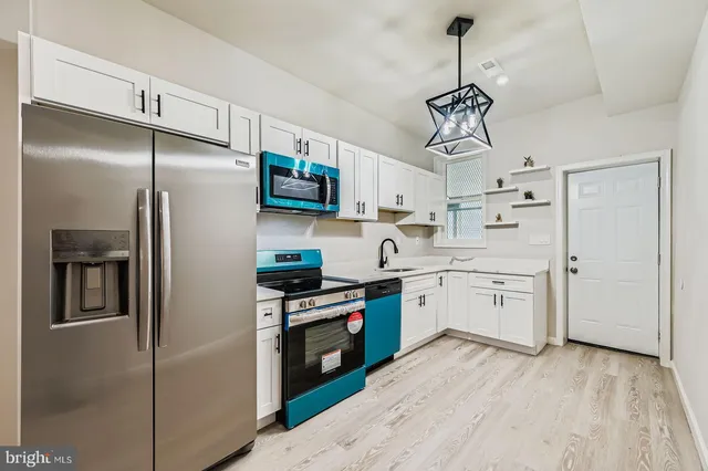 a kitchen with stainless steel appliances a refrigerator a sink and white cabinets