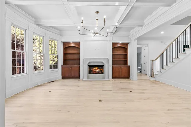 a view of a livingroom with a fireplace chandelier and windows