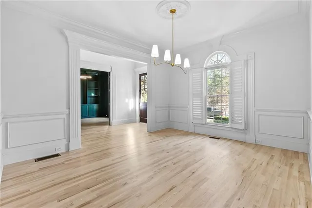 a view of a room with wooden floor chandeliers and kitchen view
