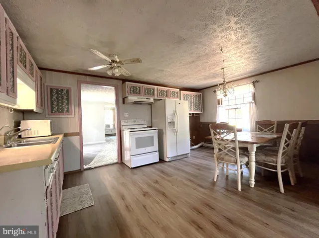 a kitchen with stainless steel appliances a dining table chairs stove refrigerator and cabinets