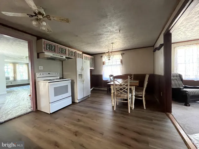 a kitchen with stainless steel appliances kitchen island granite countertop a table chairs and a refrigerator