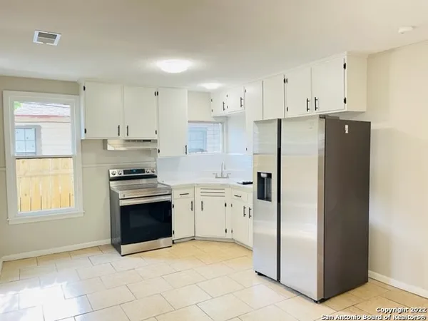a kitchen with granite countertop a refrigerator and a stove top oven