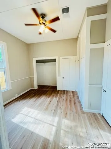 a view of a room with a ceiling fan and hardwood floor