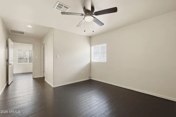 an empty room with wooden floor a ceiling fan and windows