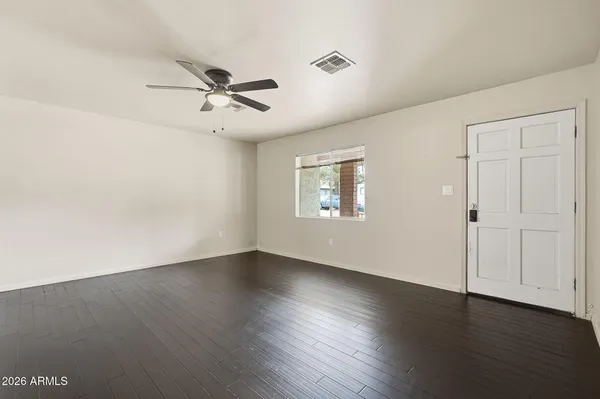 an empty room with wooden floor ceiling fan and windows