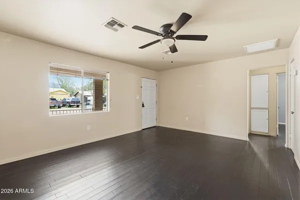 an empty room with wooden floor fan and windows