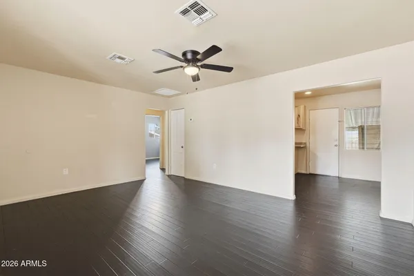 an empty room with wooden floor closet and windows