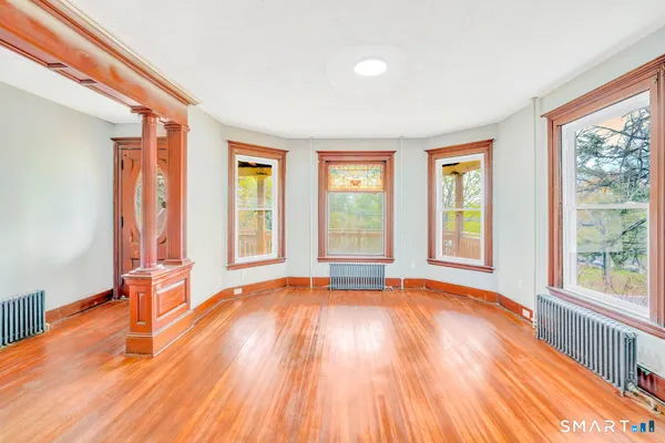 a view of an empty room with wooden floor and a window