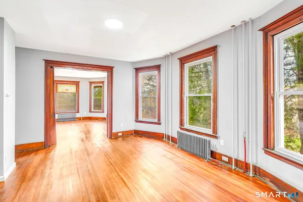 a view of an empty room with wooden floor and a window