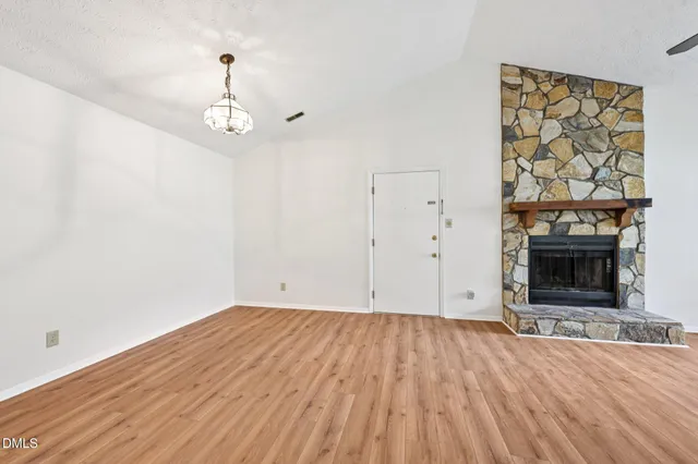 a view of empty room with wooden floor and fireplace