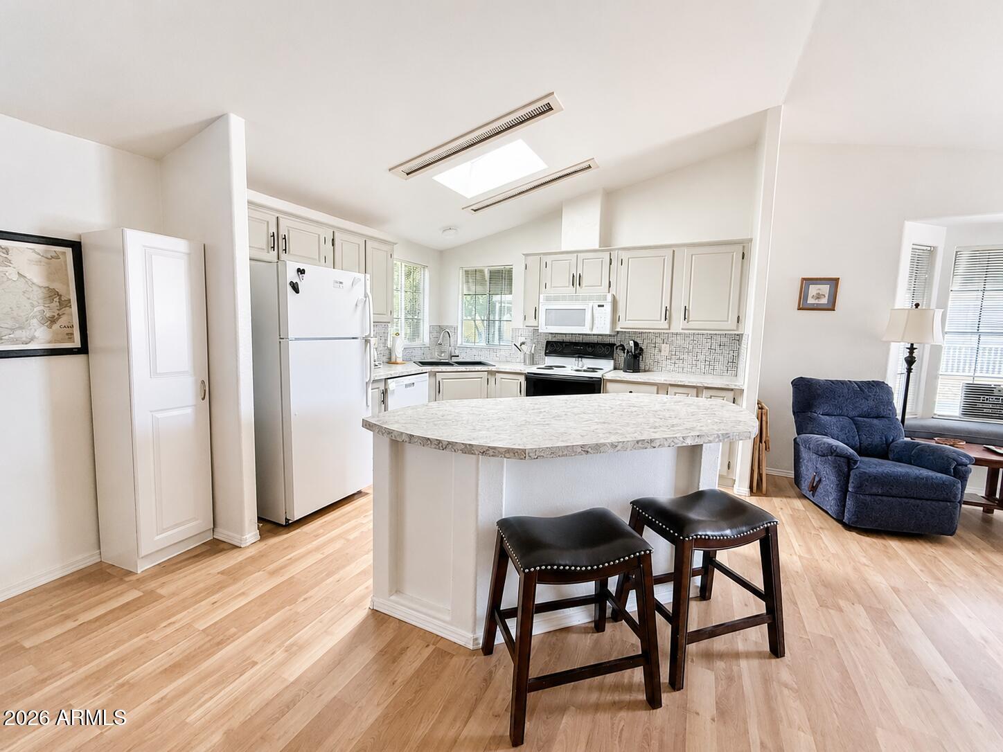 8865 East Baseline Road, Unit 103 Mesa, AZ 85209 - Photo 15 of 47 a kitchen with kitchen island a refrigerator a stove a dining table and chairs with wooden floor