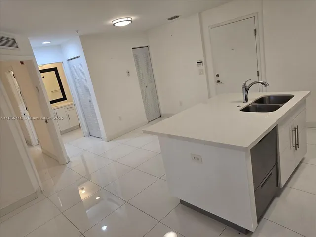 a kitchen that has a sink a refrigerator and cabinets