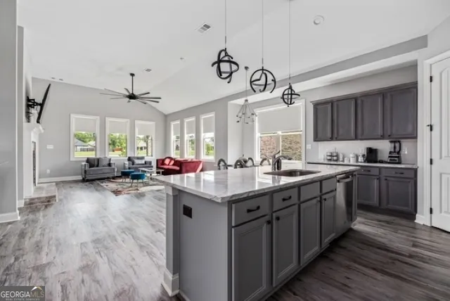 a kitchen with kitchen island a island wooden floors stainless steel appliances a sink and cabinets