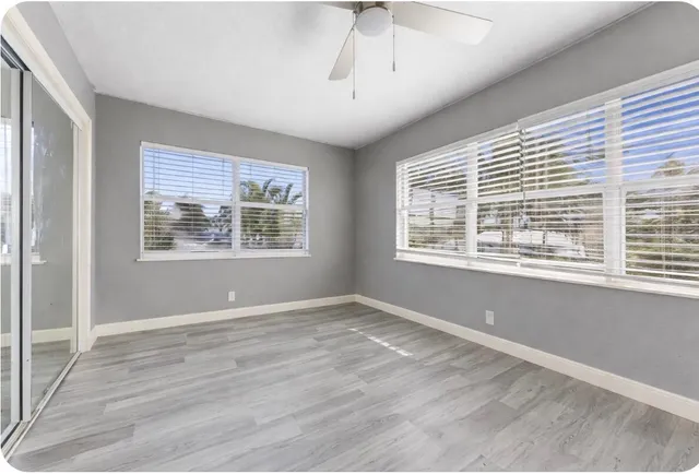 a view of an empty room with a window and wooden floor