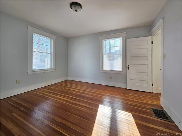 a view of an empty room with wooden floor and window