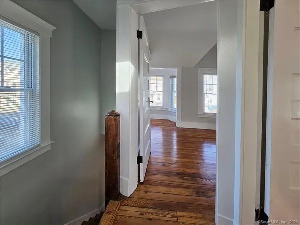 a view of a hallway with wooden floor and staircase