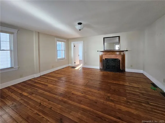 a view of empty room with wooden floor and fireplace