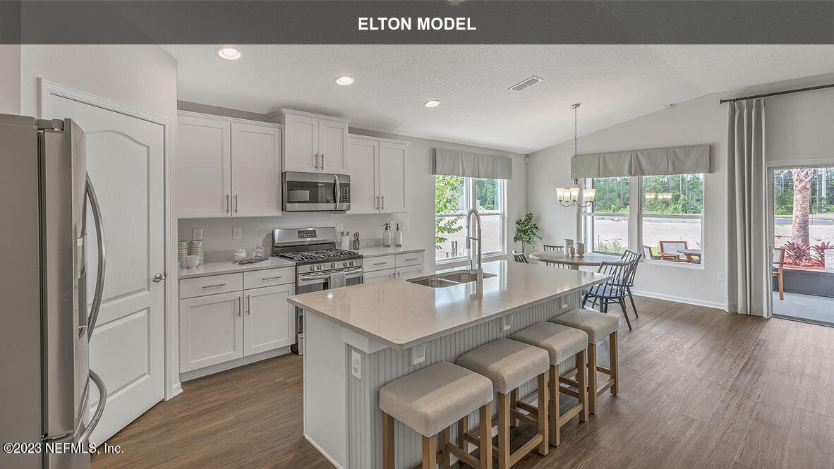 65 Zancara Street St. Augustine, FL 32084 - Photo 4 of 45 a kitchen with stainless steel appliances granite countertop a stove top oven a refrigerator a sink and a dining table with wooden floor