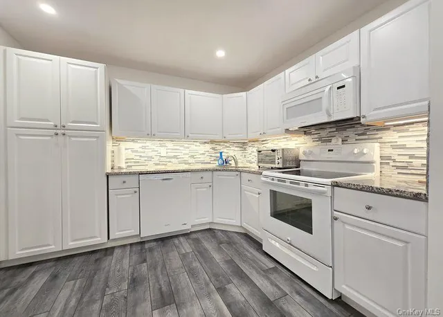 a kitchen with granite countertop white cabinets and white appliances