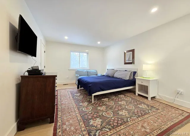 a spacious bedroom with a bed and a flat screen tv