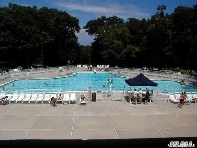 a view of swimming pool with seating space and trees in the background
