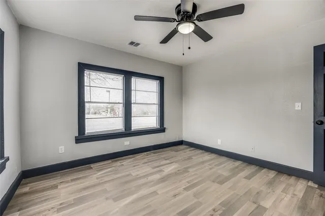 an empty room with a window and a fan