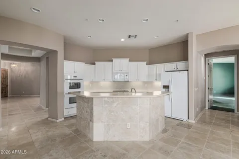 a kitchen with granite countertop white cabinets and refrigerator