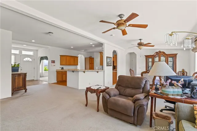 a living room with furniture kitchen view and a chandelier