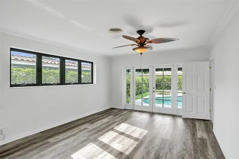 a view of empty room with wooden floor and fan