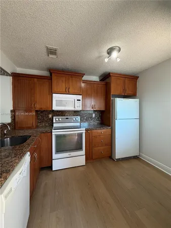 a kitchen with granite countertop white cabinets and stainless steel appliances