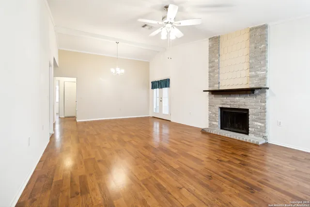 a view of an empty room with wooden floor and a fireplace