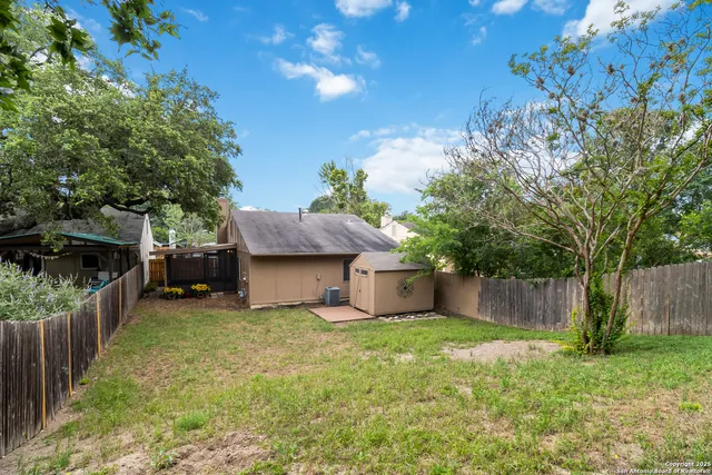 a view of a house with a yard and a large tree