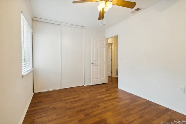 an empty room with a wooden floor and a ceiling fan