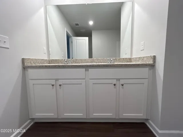 a bathroom with a granite countertop bathtub sink vanity mirror and toilet