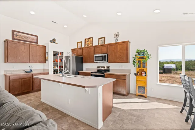 a kitchen with stainless steel appliances kitchen island granite countertop a refrigerator and a stove top oven