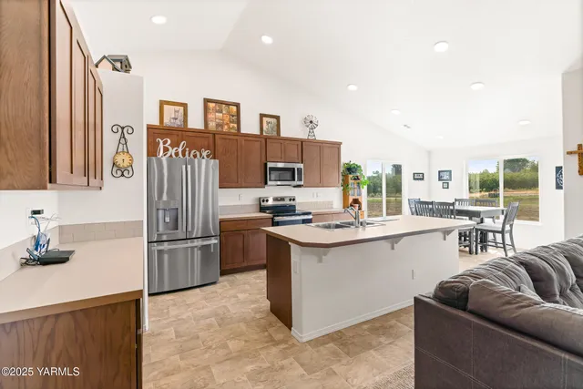 a kitchen with stainless steel appliances kitchen island granite countertop a refrigerator and a stove top oven