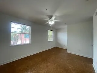 an empty room with windows and fan